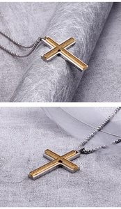Detailed close-up of double-layer silver and gold cross pendant on a textured surface