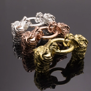 Comparaison détaillée de fermoirs dragon vintage en argent, or et or rose sur fond noir
