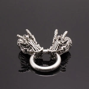Détail macro d'une bague tête de dragon argentée vintage aux textures sur verre noir