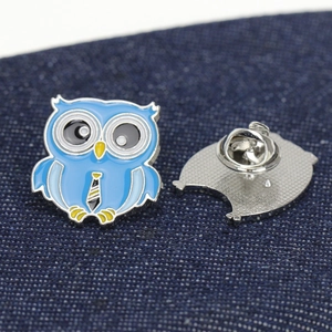 Détail d'une broche hibou en émail bleu avec cravate rayée et fermoir papillon en métal