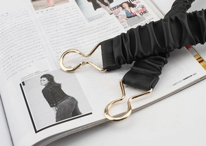 Detail view of elastic waist belt with black leather texture and gold metal clips