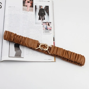 Brown elastic wide waist belt with golden interlocking circles on fashion magazine