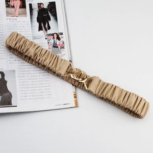 Detail of khaki elastic corset belt with a golden circular cross buckle on a magazine