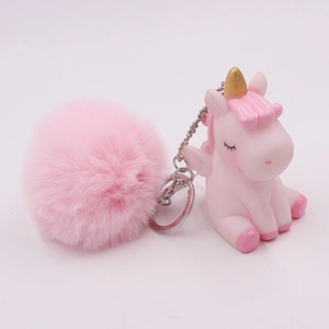 Detail of pink unicorn keychain featuring a golden horn and a large fluffy fur pompom