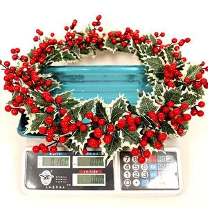 Détail d'une couronne de Noël artificielle avec baies rouges et feuilles bordées de blanc