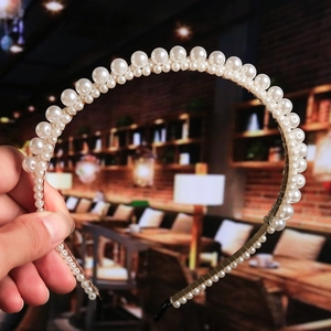 Detailed view of elegant white pearls in gradient sizes on a golden metal headband