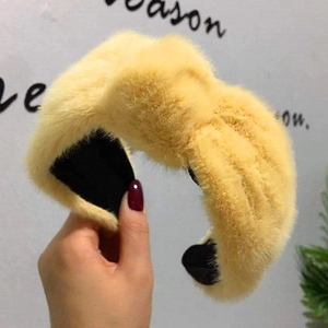 Dettaglio della morbida fascia in peluche gialla con nodo per l'acconciatura invernale.
