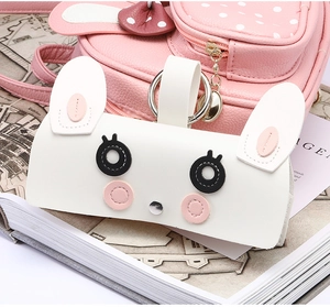 Vue détaillée d'un étui à lunettes lapin en cuir blanc accroché à un sac à dos