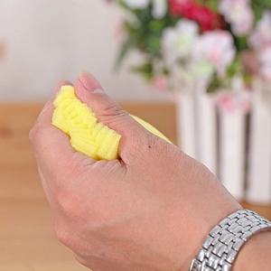 Durable yellow porous sponge brush being squeezed by a hand to show softness and elasticity