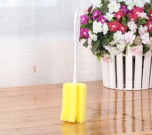 Detail view of a yellow sponge cleaning brush with a durable white plastic handle