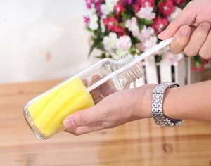 Detail of yellow sponge cup brush cleaning a glass bottle with durable white handle