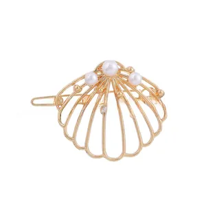 Détail de la barrette coquillage dorée avec cinq perles nacrées et strass brillants