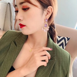 Close-up of long drop glass bead earrings and gold necklace on a fashion model