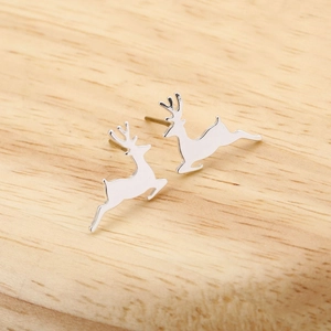 Macro shot of silver reindeer stud earrings showing a running pose on wood background