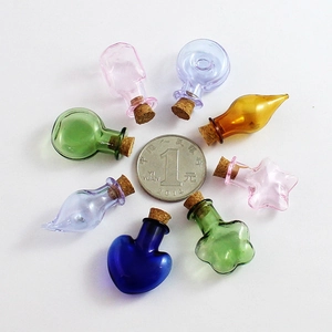 Assorted colorful mini glass jars with corks shown around a coin for size reference