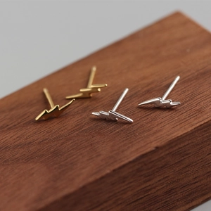 Macro shot of minimalist S925 sterling silver lightning bolt studs in gold and silver