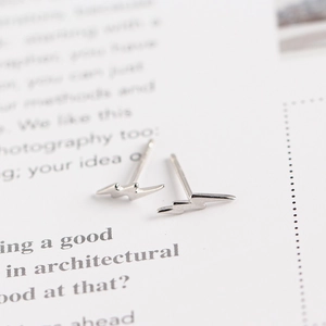 Macro shot of minimalist lightning bolt S925 sterling silver stud earrings on a paper