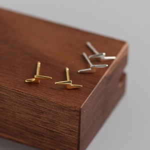 Macro view of minimalist S925 sterling silver lightning bolt studs in gold and silver