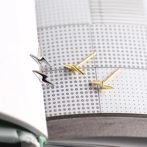 Macro detail of lightning bolt stud earrings in gold and silver finish on notebook