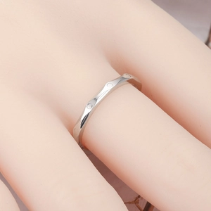 Close-up of a silver geometric titanium steel ring with a faceted diamond pattern