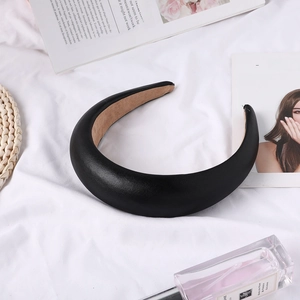 Detail of a padded black leather headband with non-slip interior on a stylish white fabric