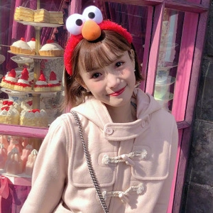 Detailed view of the red plush Elmo hairband worn on a model against a soft pink background