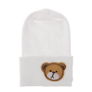 Close-up of white knitted baby beanie featuring a cute brown bear embroidery patch