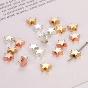 Detailed view of tiny star-shaped jewelry beads in gold, silver, and rose gold finishes