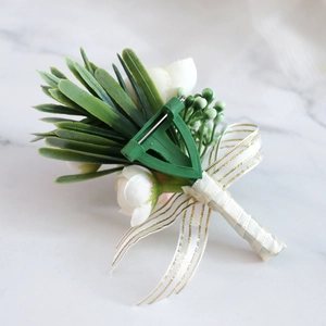 Handmade white faux flower boutonniere with green leaves and gold-edged ribbon