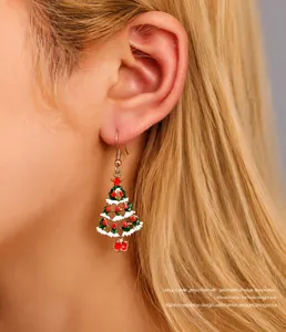 Détail d'une boucle d'oreille sapin de Noël en émail vert avec boîte cadeau rouge