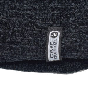 Close-up of thick chenille knit texture and brand logo tag on black winter beanie