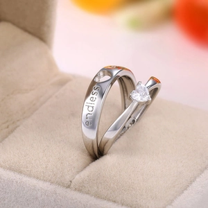 Polished silver heart ring with endless engraving and heart-shaped gemstone on velvet