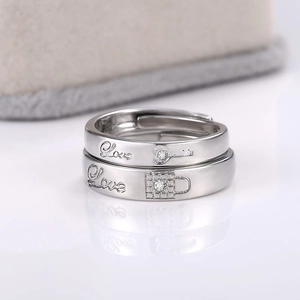 Detailed view of silver couple rings with Love engraving and heart lock zirconia design