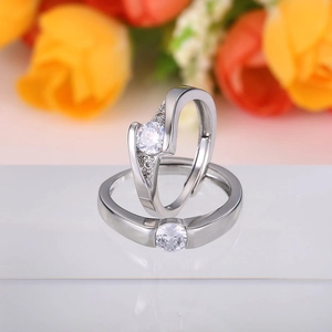 Macro shot of silver couples rings with round cubic zirconia on warm floral background