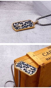 Macro shot of a rectangular leopard print pendant with a rhinestone cross on a silver chain
