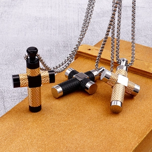 Drei Herren-Kreuzanhänger aus Titanstahl in Gold, Schwarz und Silber auf Holzgrund