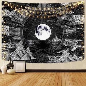 Detail of bohemian wall tapestry with moon and mountain patterns under warm fairy lights