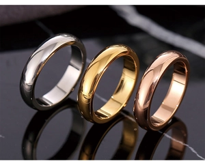 Polished stainless steel wide rings in silver, gold, and rose gold on marble surface