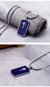 Detail of silver stainless steel cross pendant on deep blue dog tag with metal chain