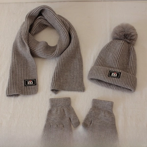 Flat lay of light grey knitted winter set showing detailed beanie texture and faux fur pom