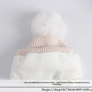 Detail of winter knit hat with large faux fur pom-pom and soft plush lining texture