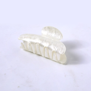 Detail of a large pearlescent white acetate hair claw clip on a minimalist background