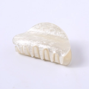 Detailed macro view of pearly white acetate claw clip with marble texture and grip teeth