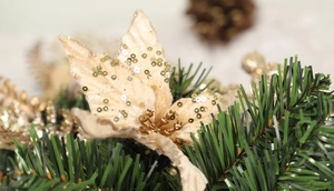 Macro shot of artificial beige flower with gold sequins and green pine needles decoration