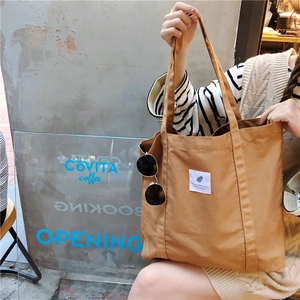 Detail of minimalist coffee-colored canvas tote bag featuring a white square fabric label