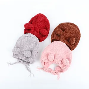 Detailed view of knitted baby earflap hats with pom-poms and warm chenille texture