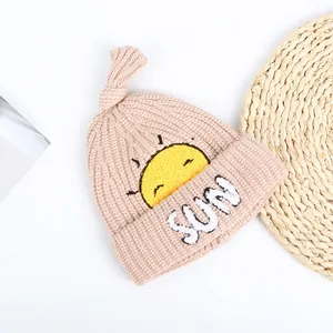 Close-up of baby knit hat showing sun embroidery and white plush SUN lettering