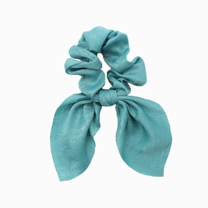 Detail of teal satin fabric hair scrunchie with rabbit ear bow on a white background