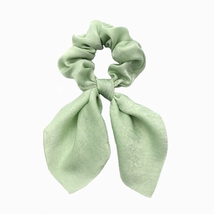 Close-up of mint green satin hair scrunchie with bow tie and smooth silk texture