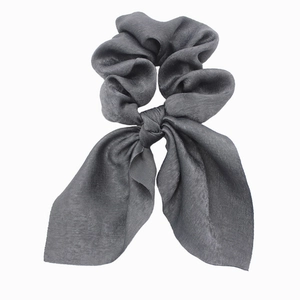 Detailed close-up of dark grey satin scrunchie with long bow ribbon ties on white background
